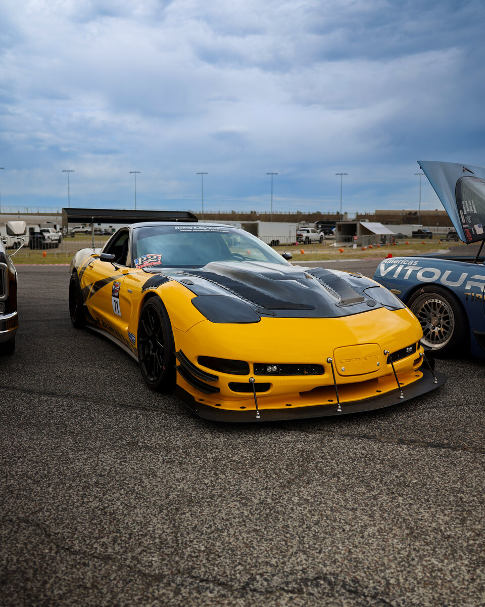 Yellow C5 Corvette Z06 staged on the grid at LS Fest Texas under overcast sky