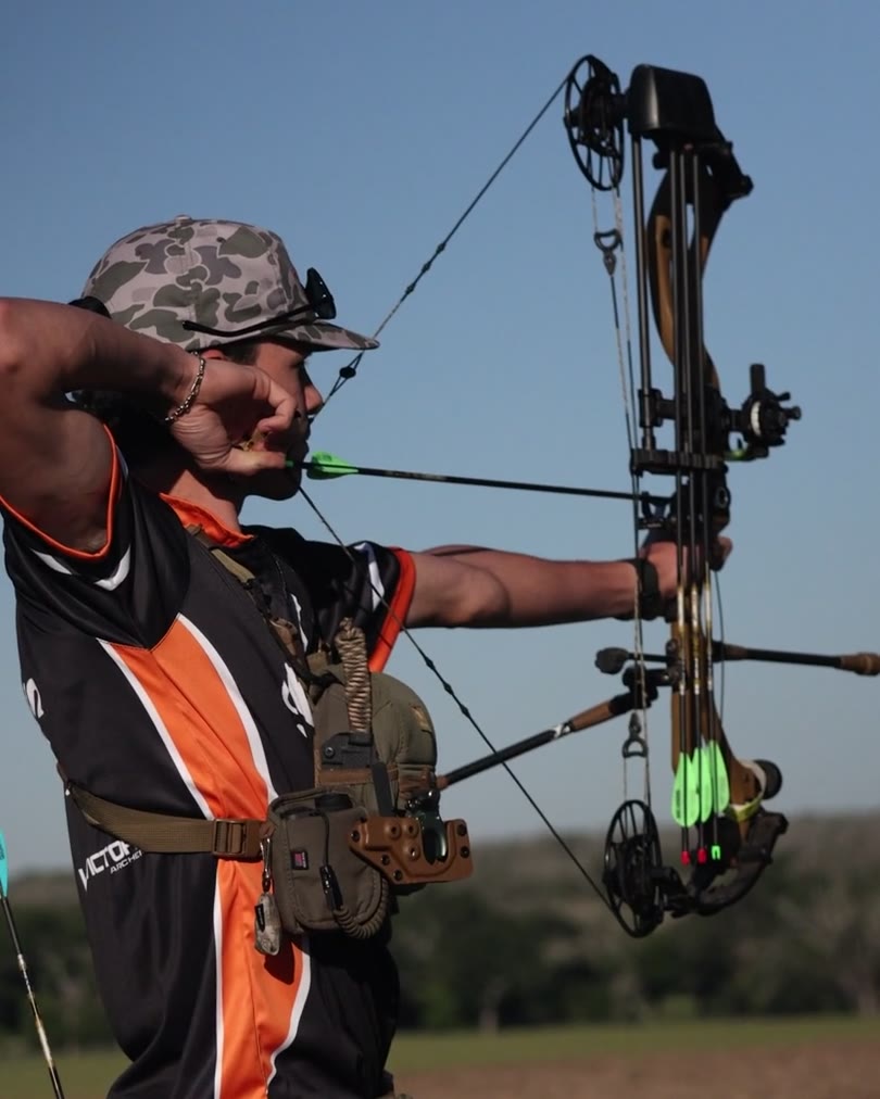 Archer at full draw against a clear blue sky