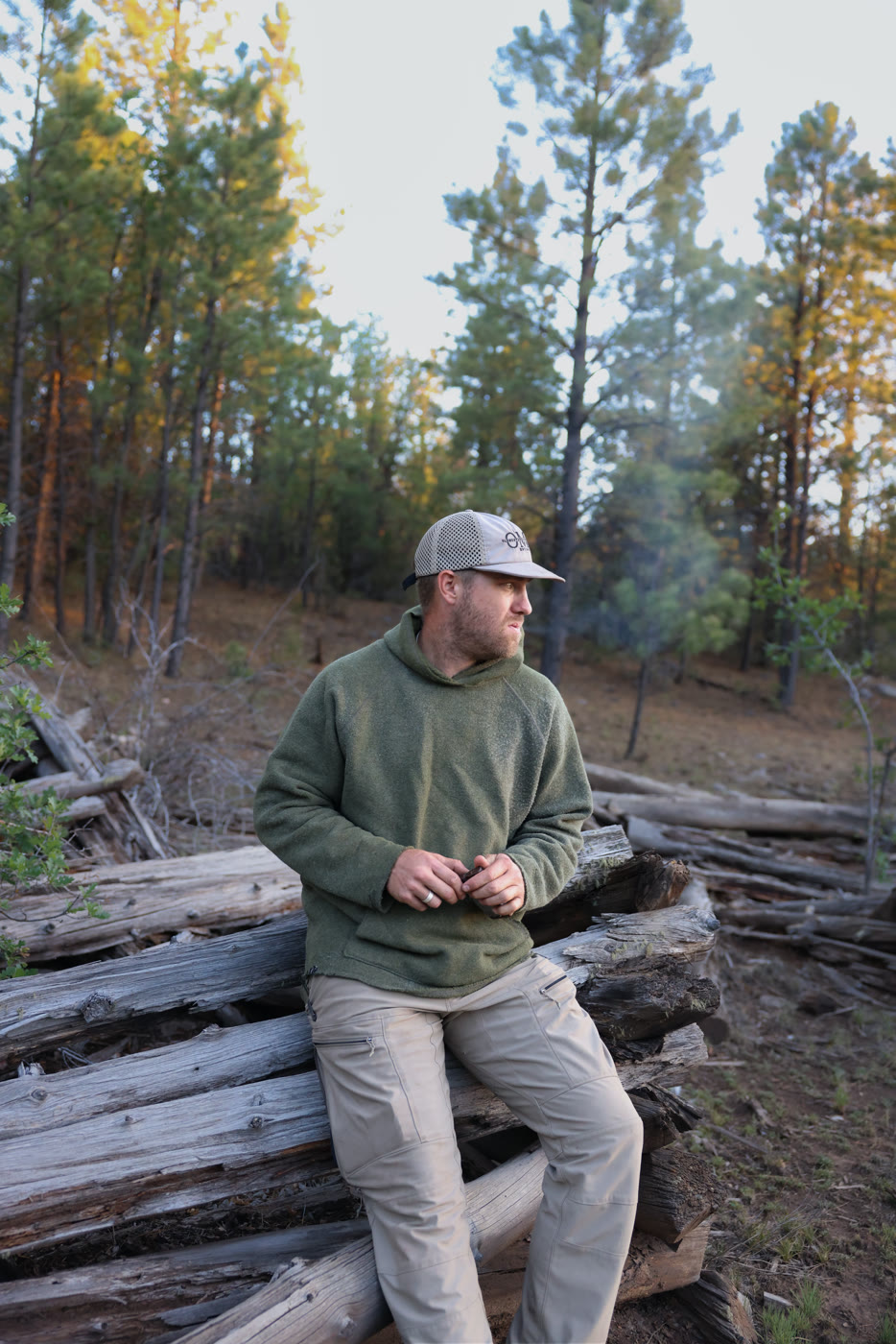 Hunter sitting on a woodpile in contemplative evening light